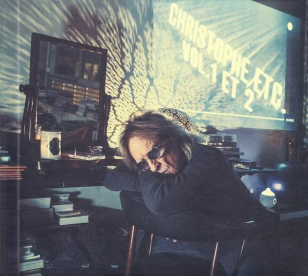 Pochette d'album. Un homme avec des lunettes de soleil s'appuie sur un bureau, avec un miroir, des livres et un écran.