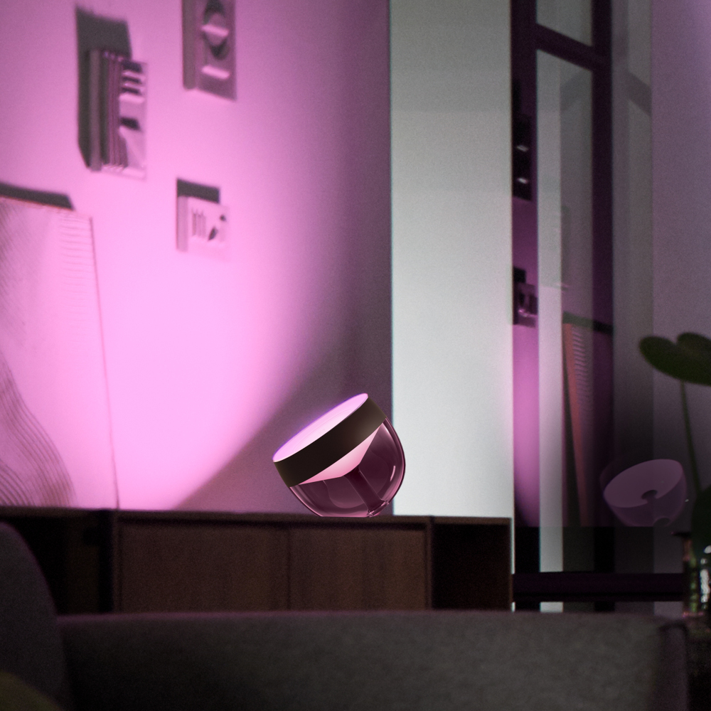 Roze lamp op een bruine kast in een kamer met foto's aan de muur.