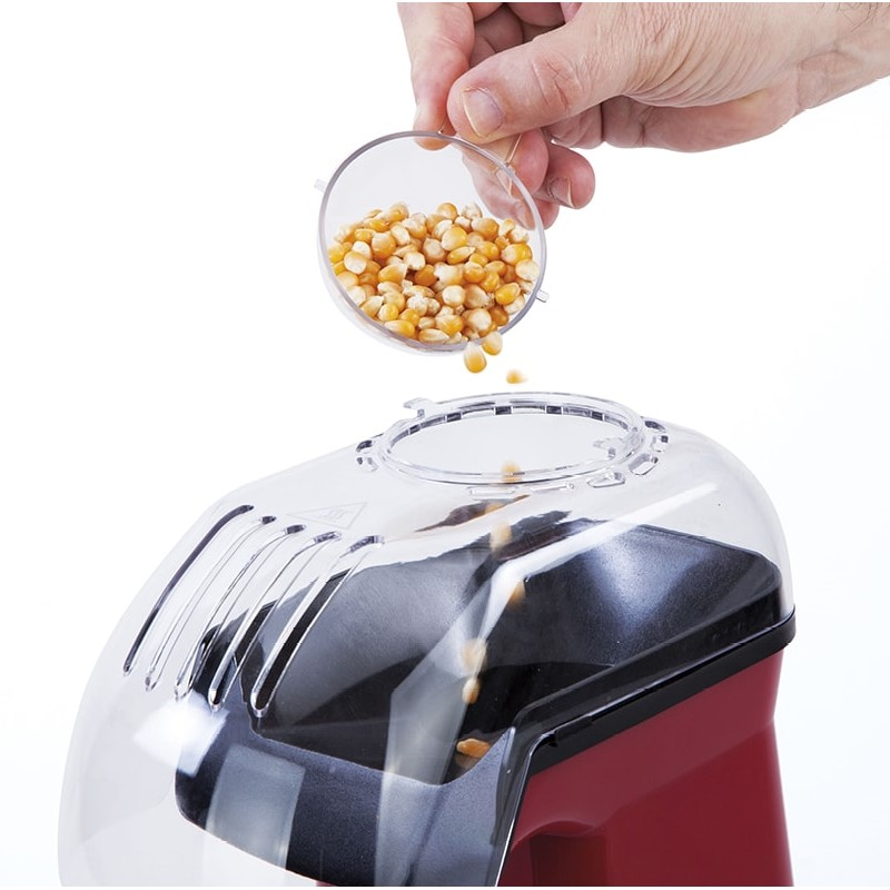 Mano vertiendo granos de palomitas en una máquina de palomitas.