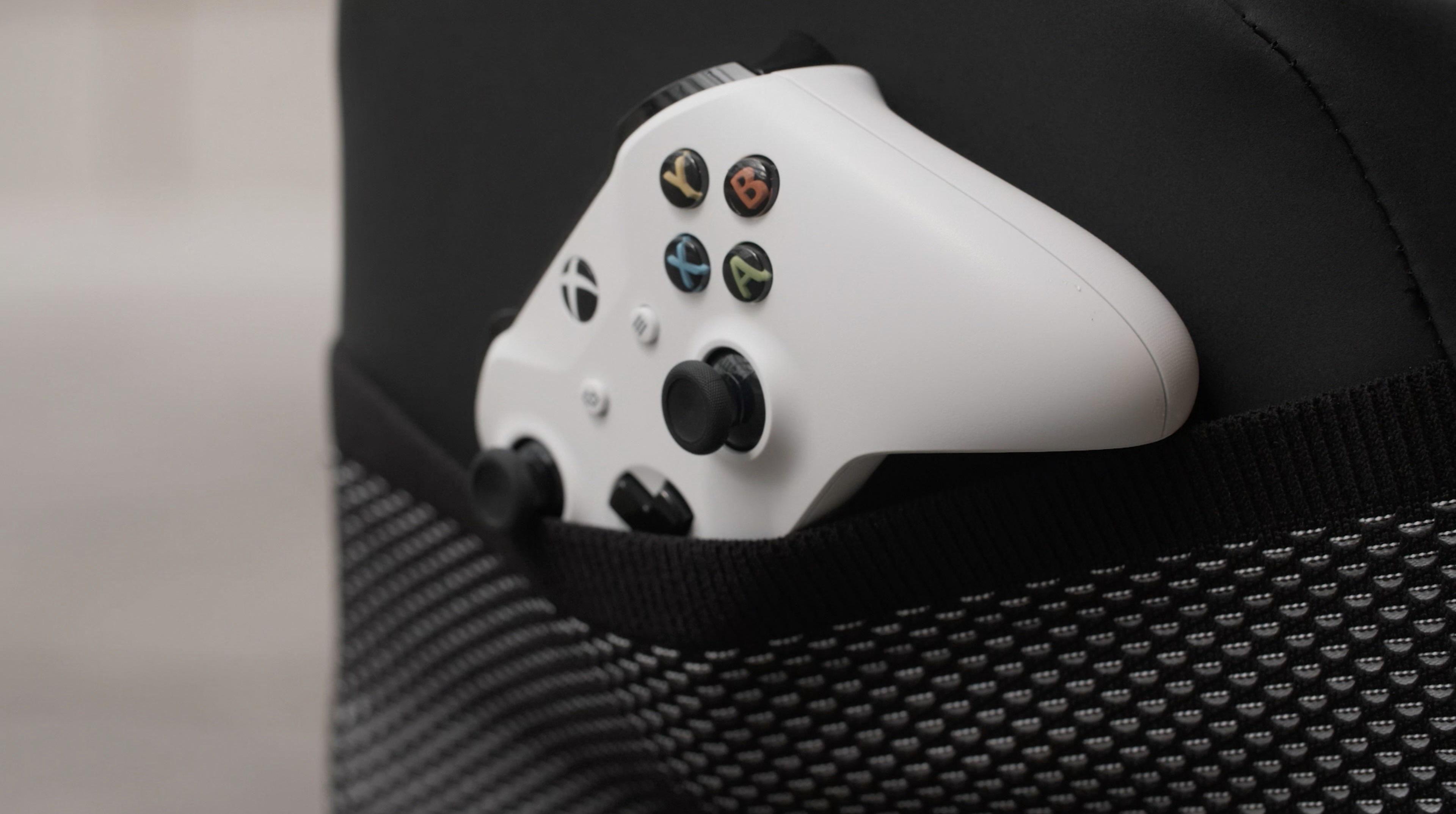Weißer Xbox-Controller in einer schwarzen Stuhltasche. Knöpfe sichtbar. Schwarzer Hintergrund.