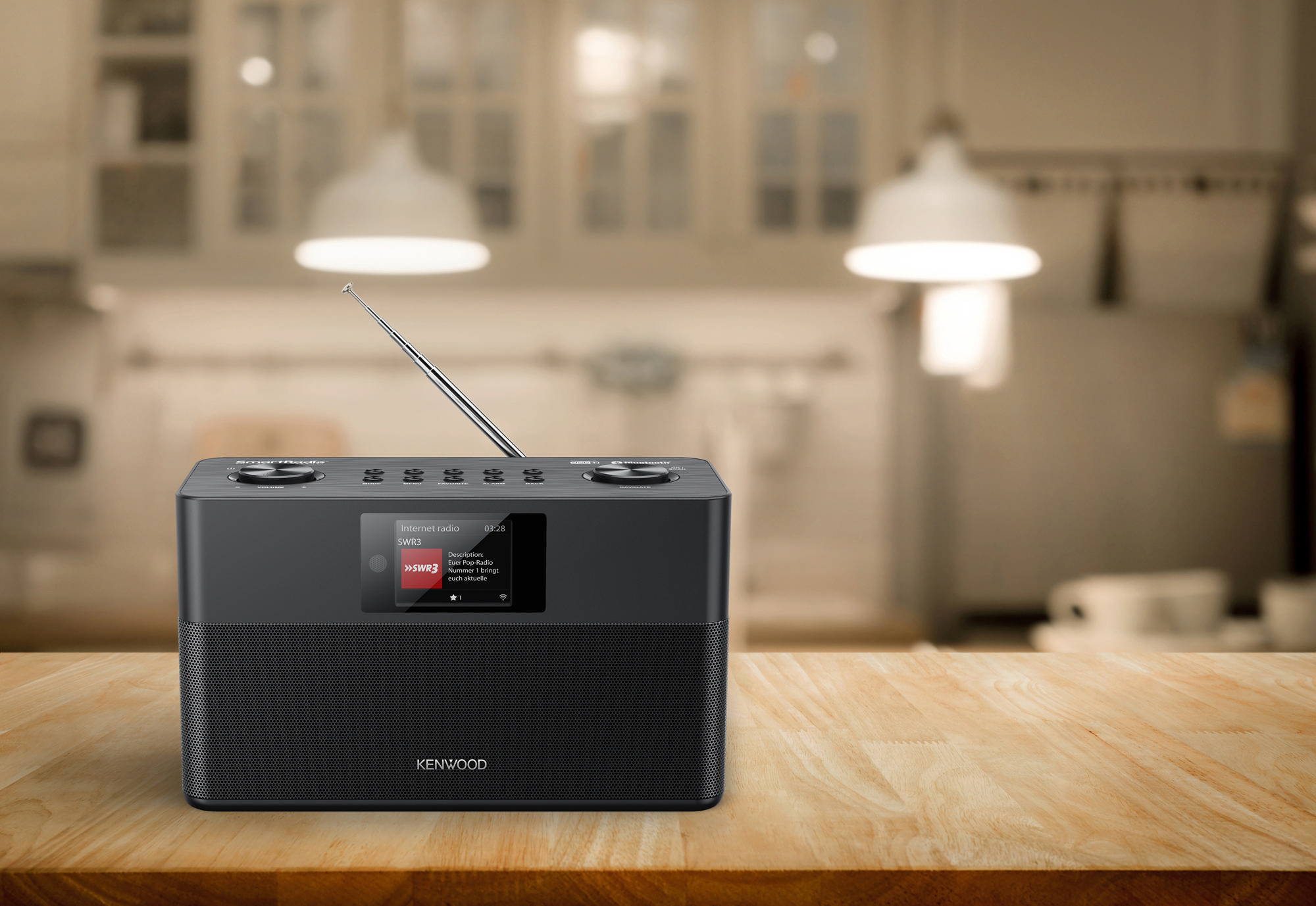 Ein schwarzes Kenwood-Radio auf einem Holztisch. Küche im verschwommenen Hintergrund.