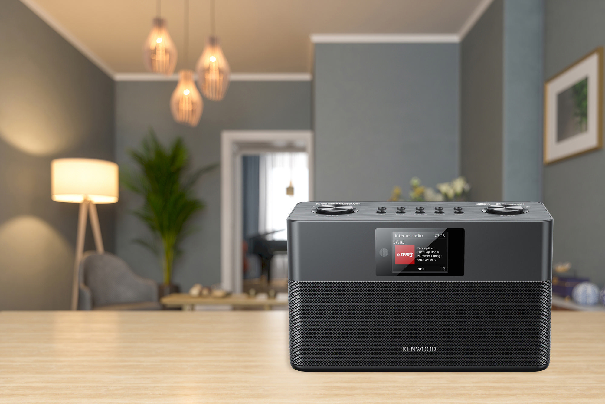 Kenwood Internetradio auf einem Holztisch, mit Lampe und Klavier im Hintergrund.