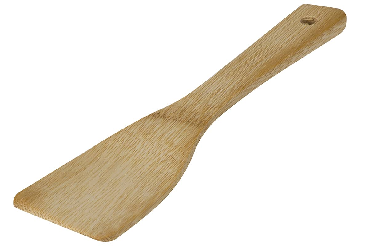 Espátula de madera, marrón claro, con una hoja plana y angulada y un mango con un agujero, sobre fondo blanco.