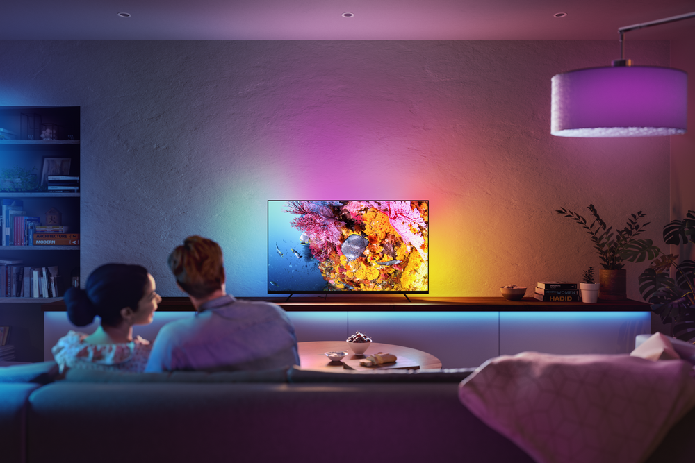 Pareja viendo la televisión con luces coloridas.