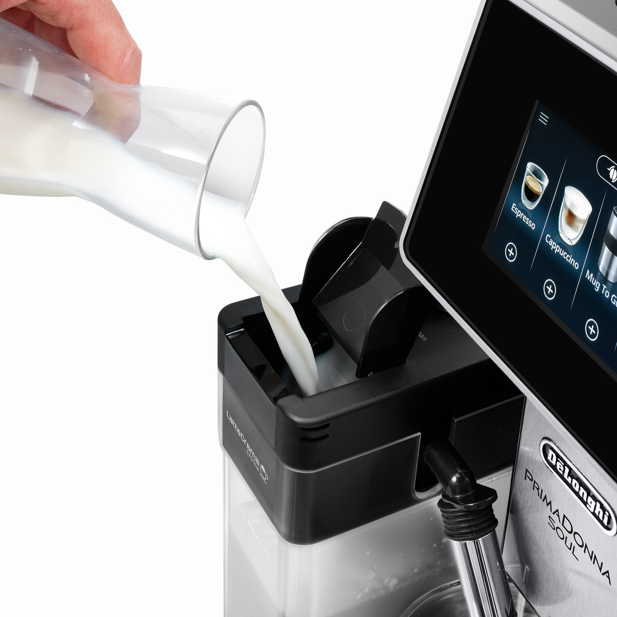 Eine Hand gießt Milch aus einem Glaskrug in den Milchbehälter einer Kaffeemaschine.