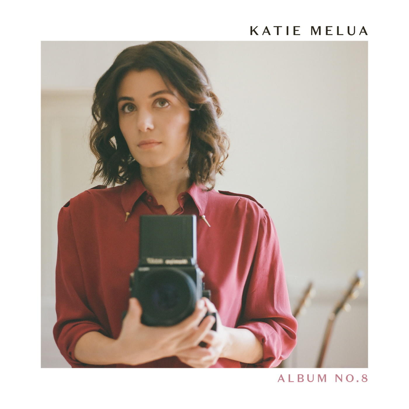 Pochette de l'album de Katie Melua. La femme tient un appareil photo. Fond blanc. Guitares à droite.