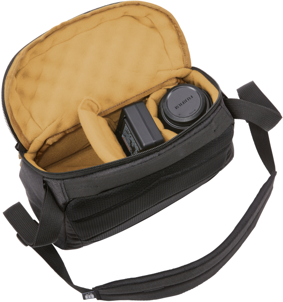 Sac photo noir ouvert, avec objectif, chargeur et compartiments internes.