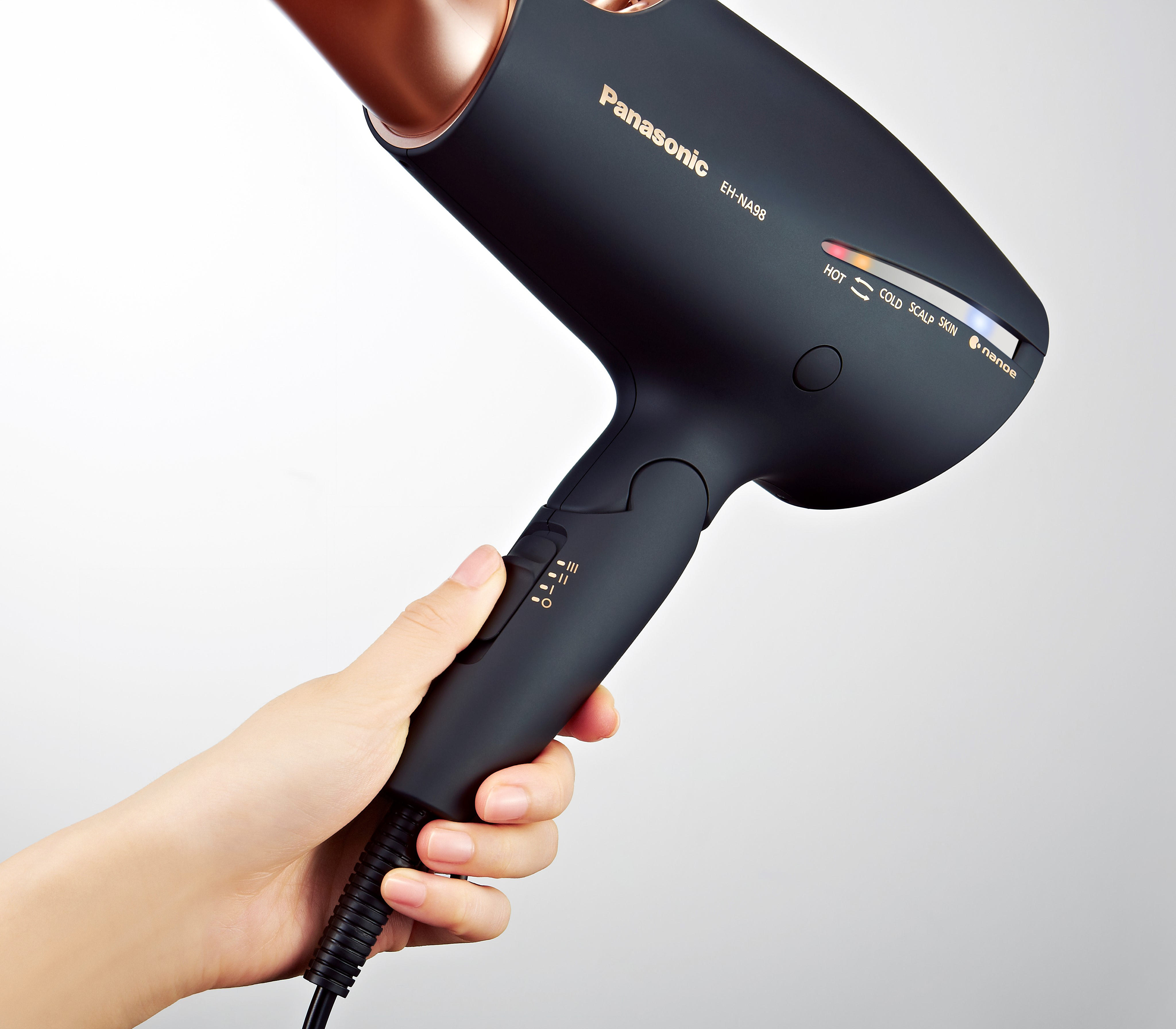 Hand hält einen schwarzen Panasonic-Haartrockner mit Bedienelementen und Anzeigen.