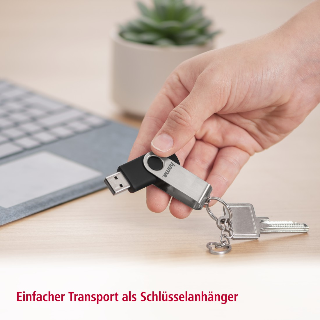 Eine Hand, die einen USB-Stick hält, der an einem Schlüsselanhänger mit Schlüsseln befestigt ist.