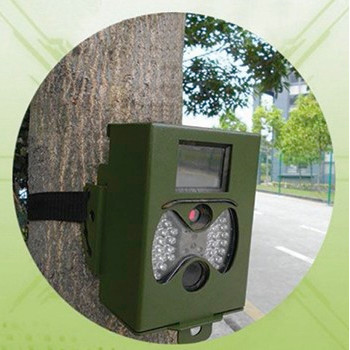Green trail camera attached to a tree trunk with a black strap.