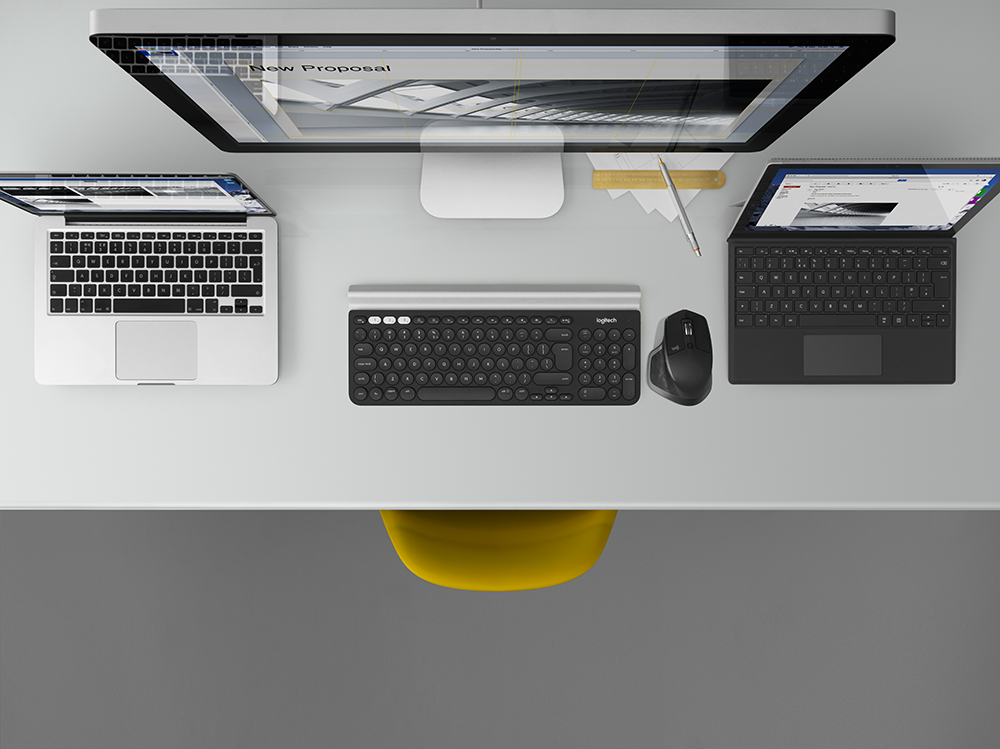 Vue aérienne d'un bureau avec un moniteur, deux ordinateurs portables, un clavier et une souris. Une chaise jaune en dessous.