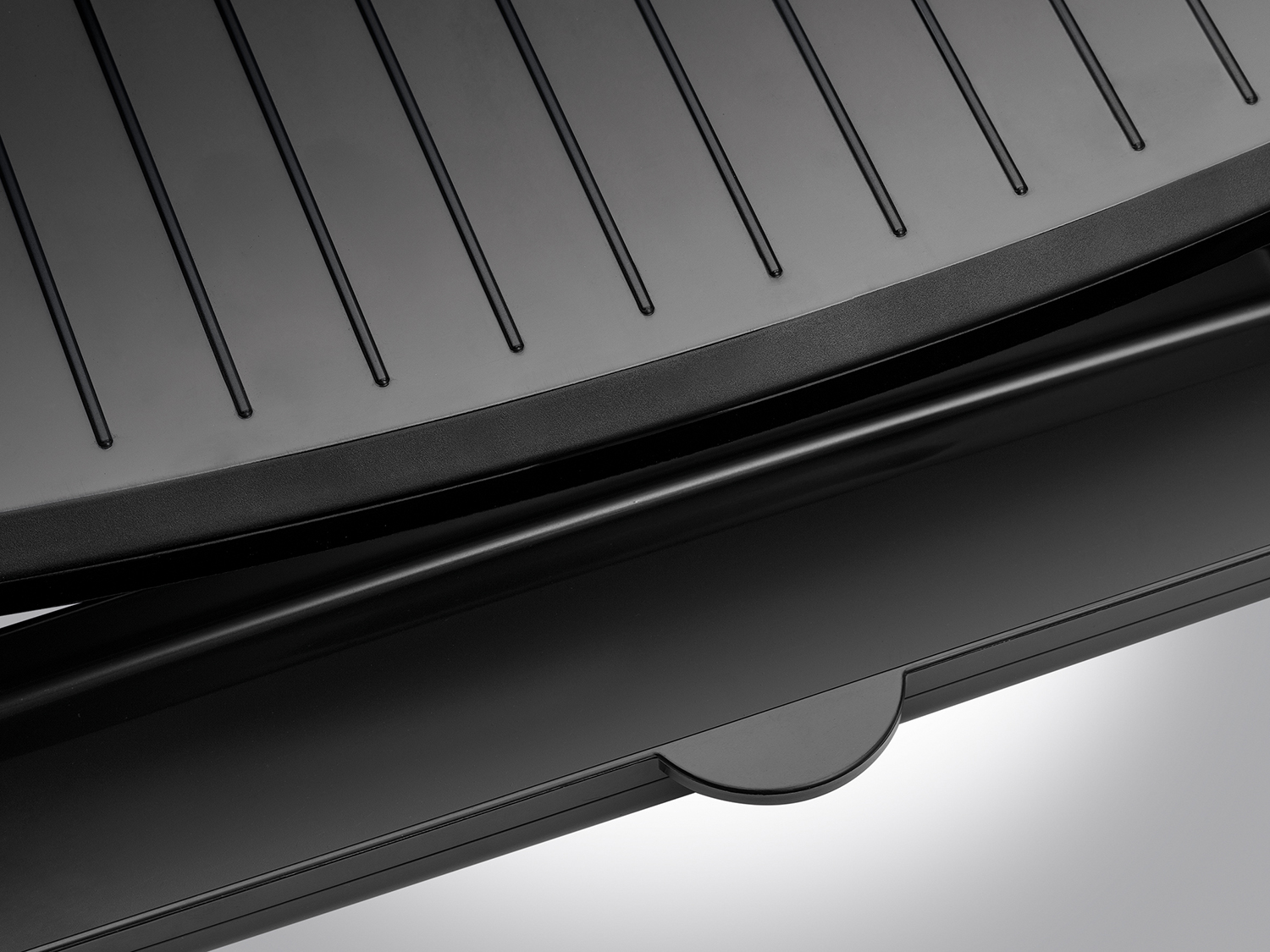 Black electric grill. The surface has grooves, and there is a lower component.