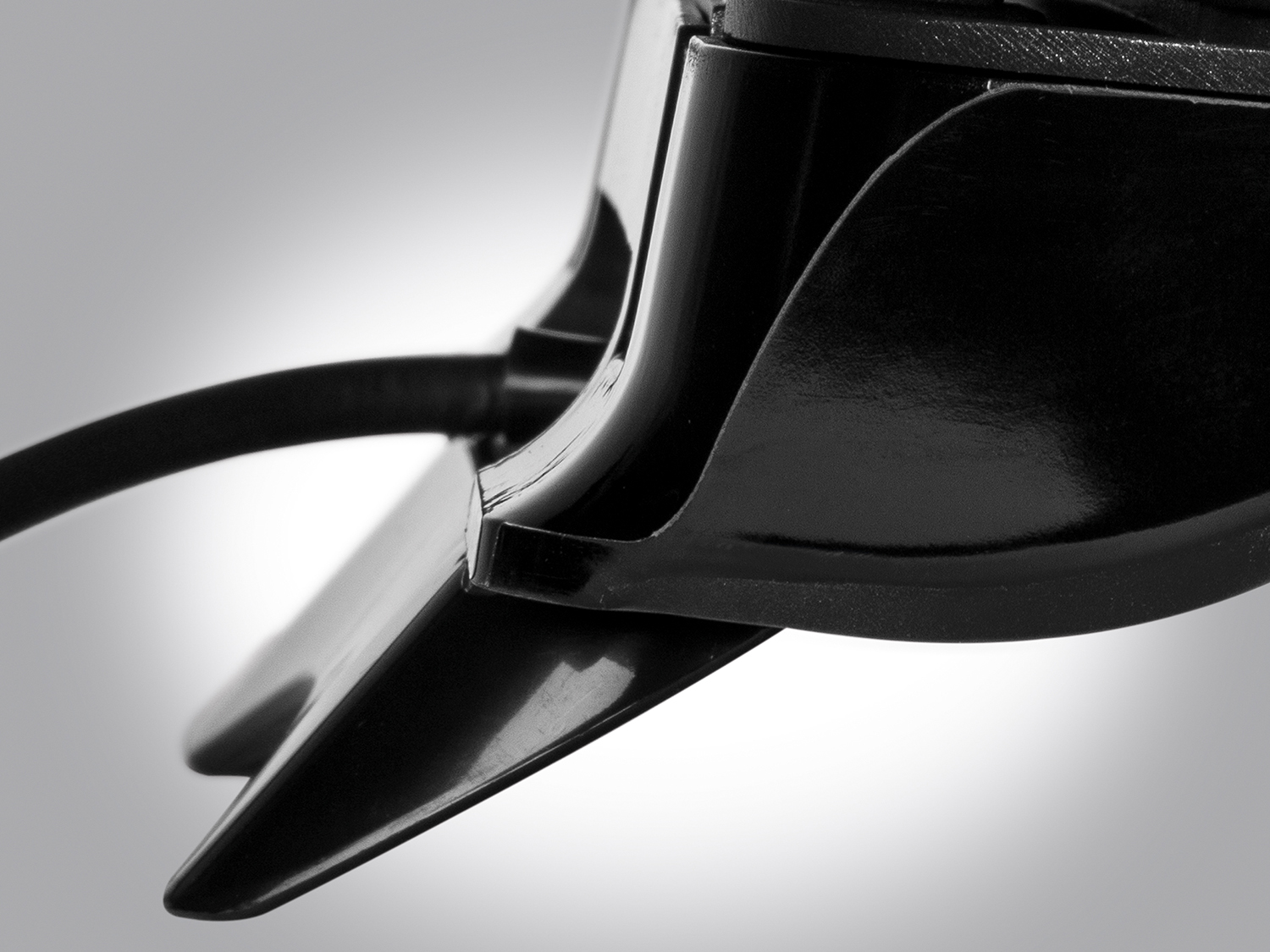 Close-up of black car part, with a sleek, angular design and a curved cable.