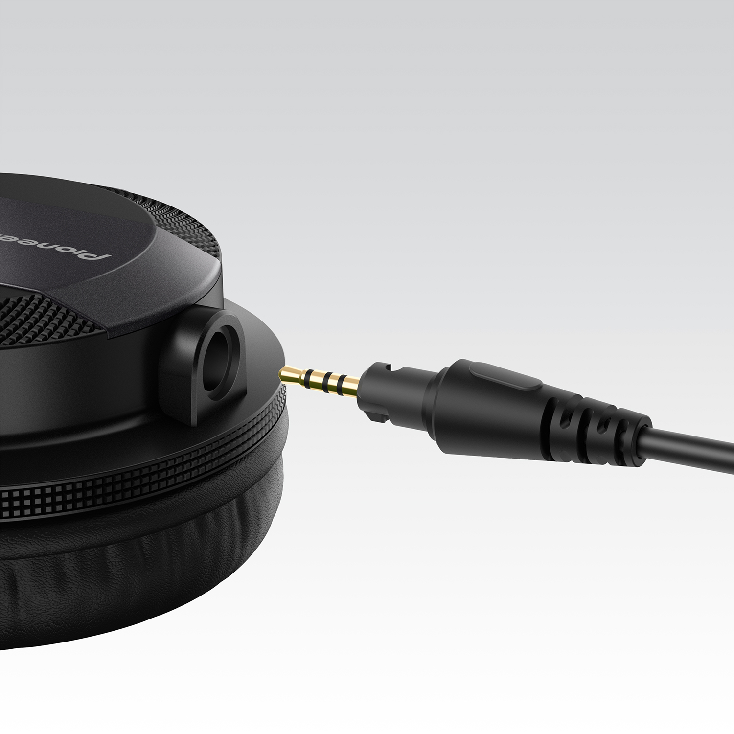 A close-up of a black Pioneer headphone jack plugged into the side of a headphone.