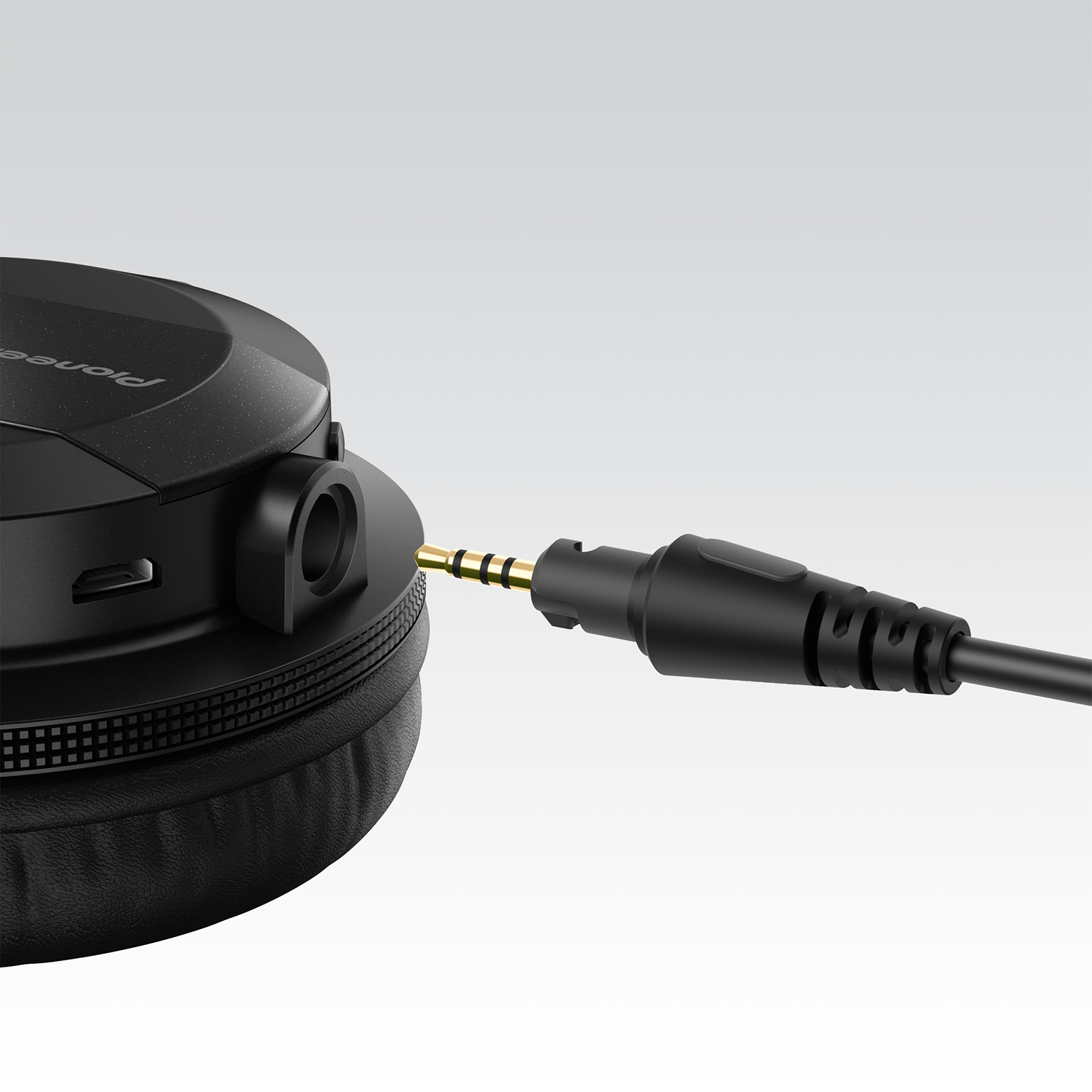 Close-up of a black headphone with a black cable and gold-colored jack inserted.