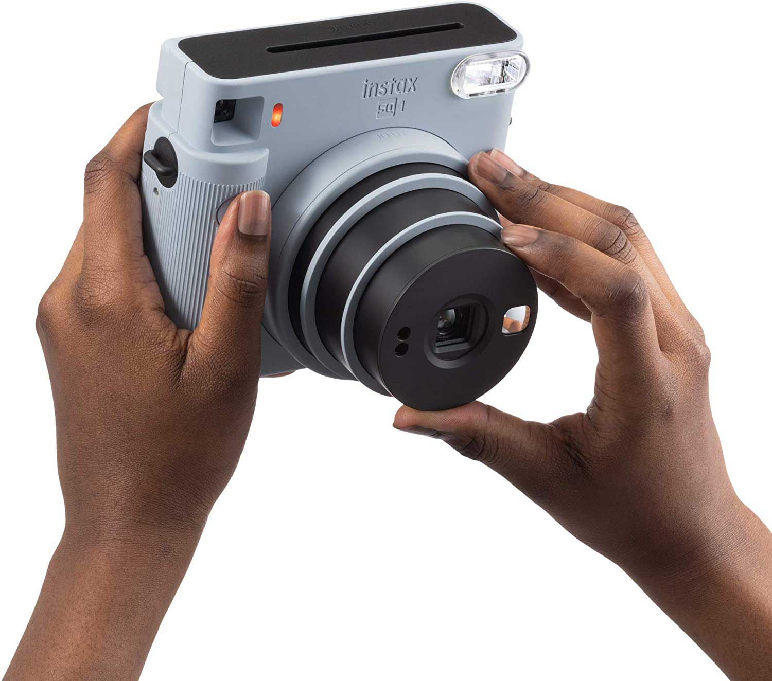 A person holding a light blue Instax camera, taking a photo.