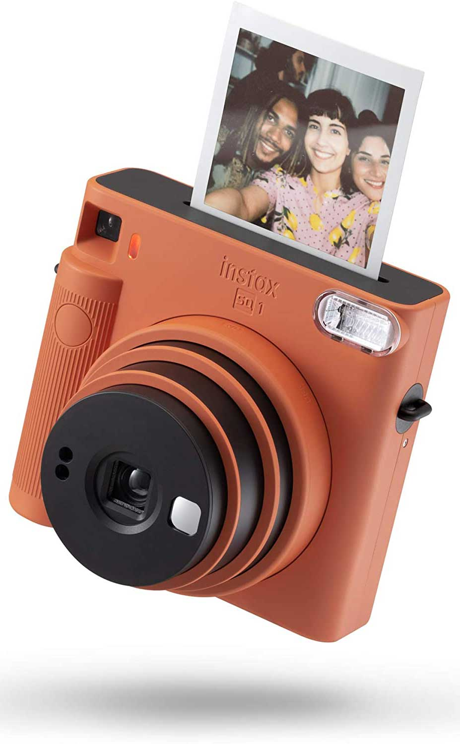 Orange Instax camera with a photo coming out, white background.