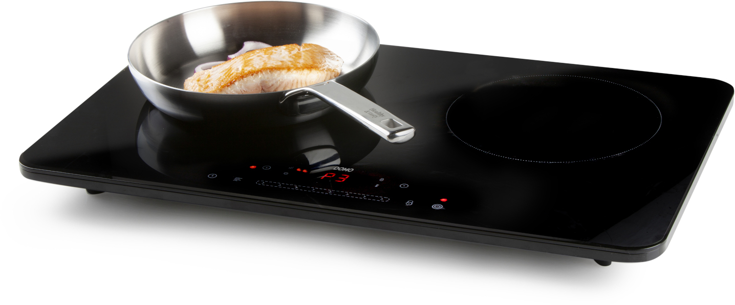 Black induction cooktop with a pan of salmon. The cooktop is on and has a control panel.