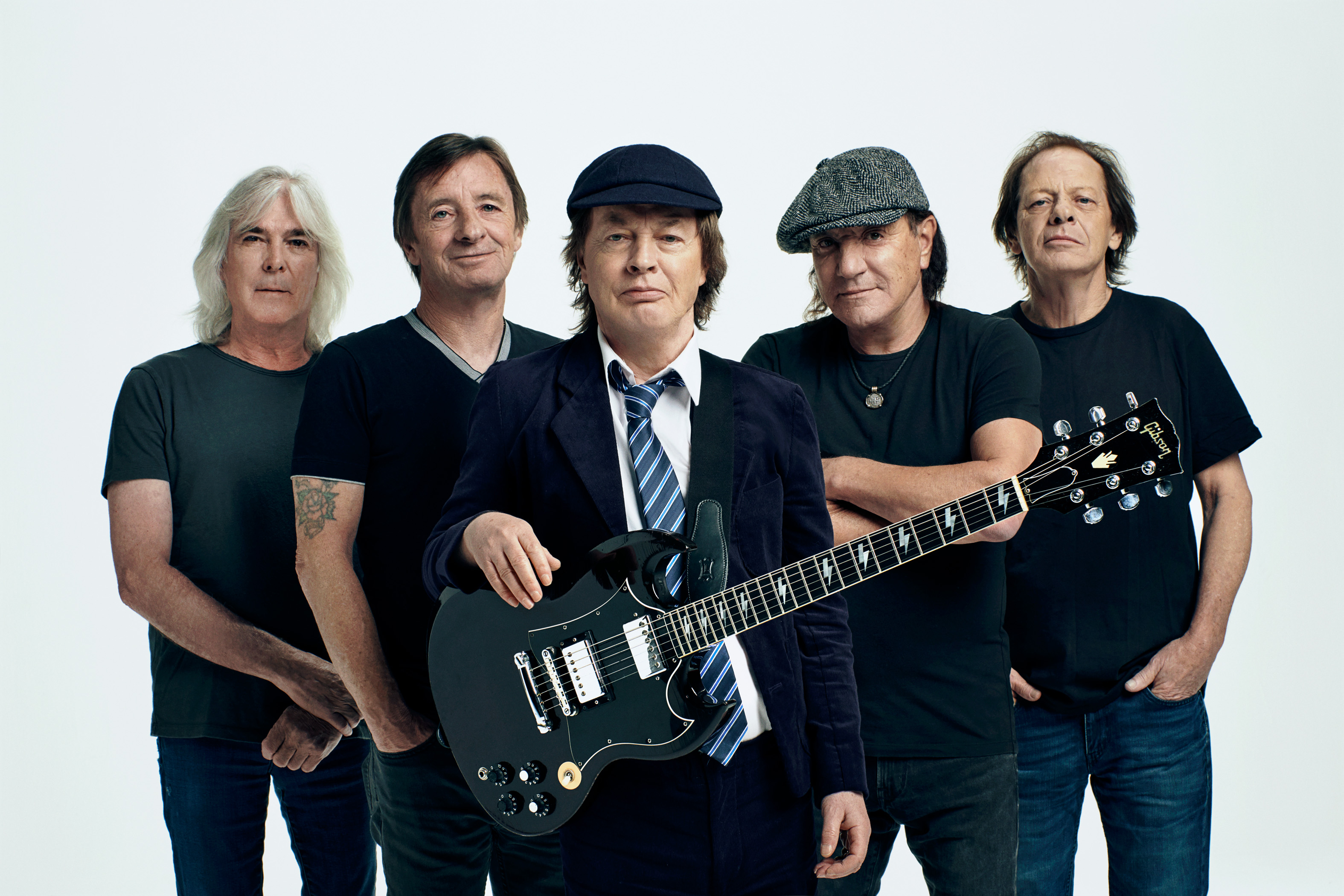 AC/DC Bandmitglieder in einem Gruppenfoto, fünf Männer, einer hält eine schwarze Gitarre.