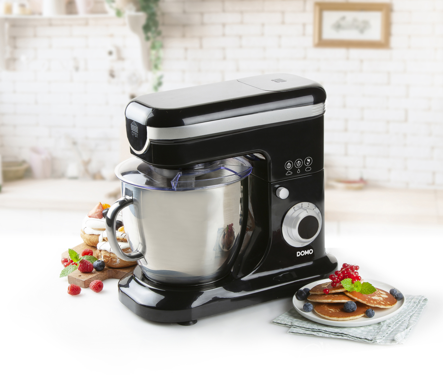 Black stand mixer with stainless steel bowl and various food items.