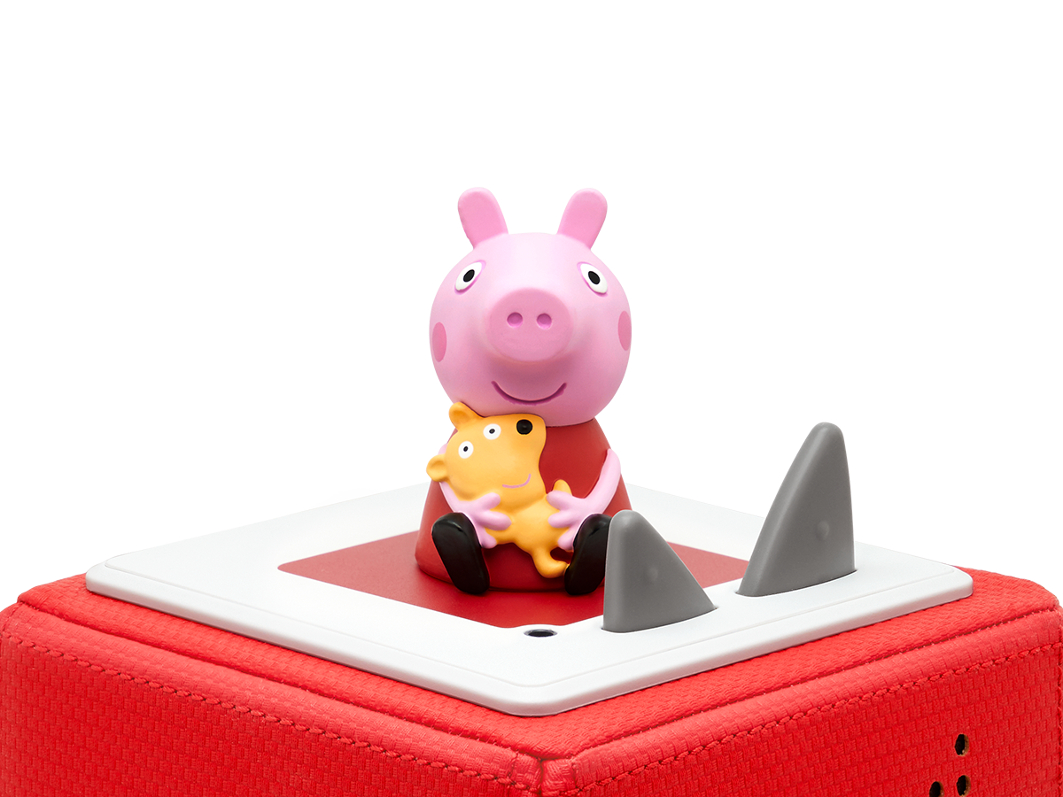 Peppa Wutz Figur. Peppa hält einen gelben Hund. Ein roter Block mit Haifischflossen ist unter ihr.