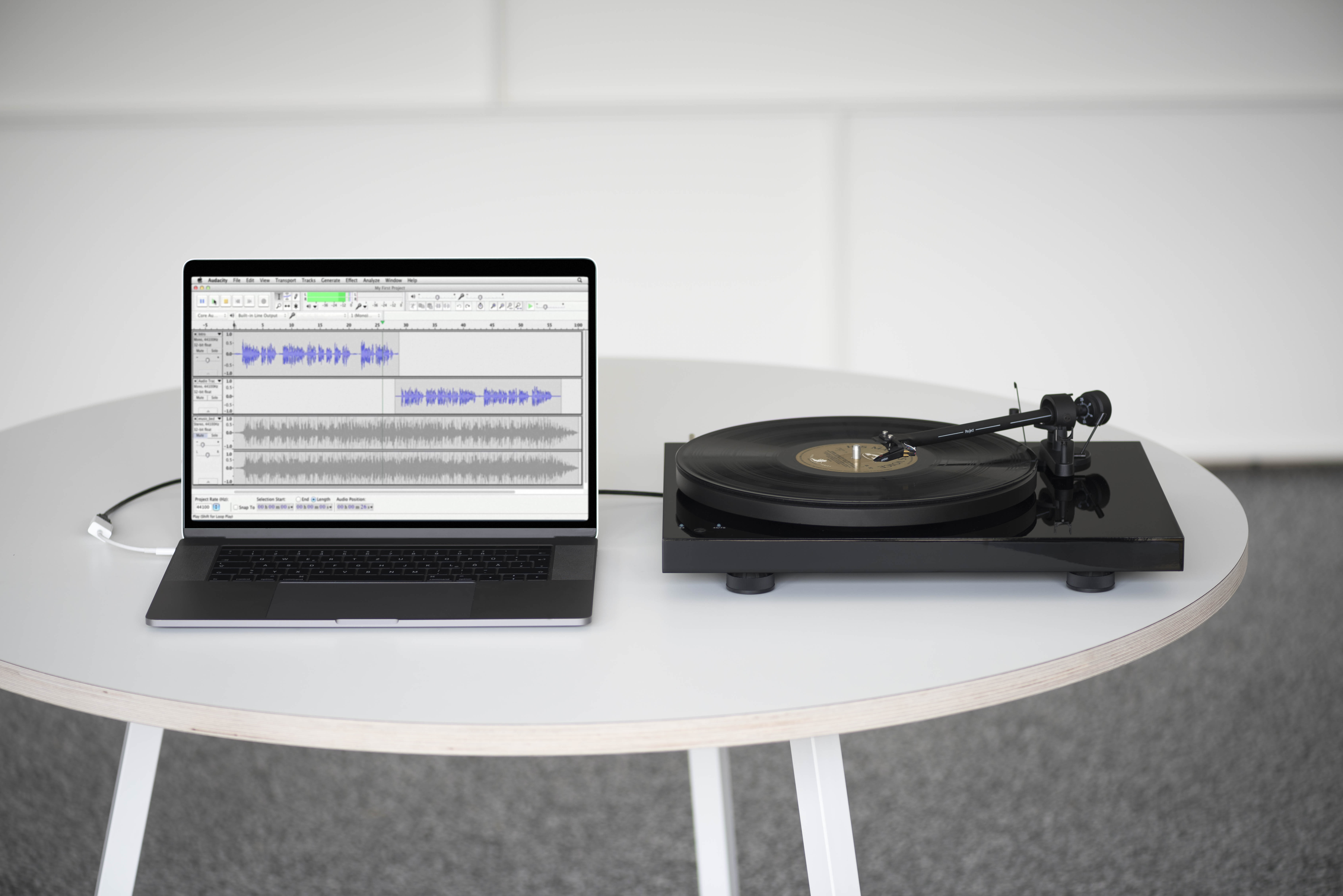 Ein Laptop und ein Plattenspieler auf einem weißen runden Tisch.