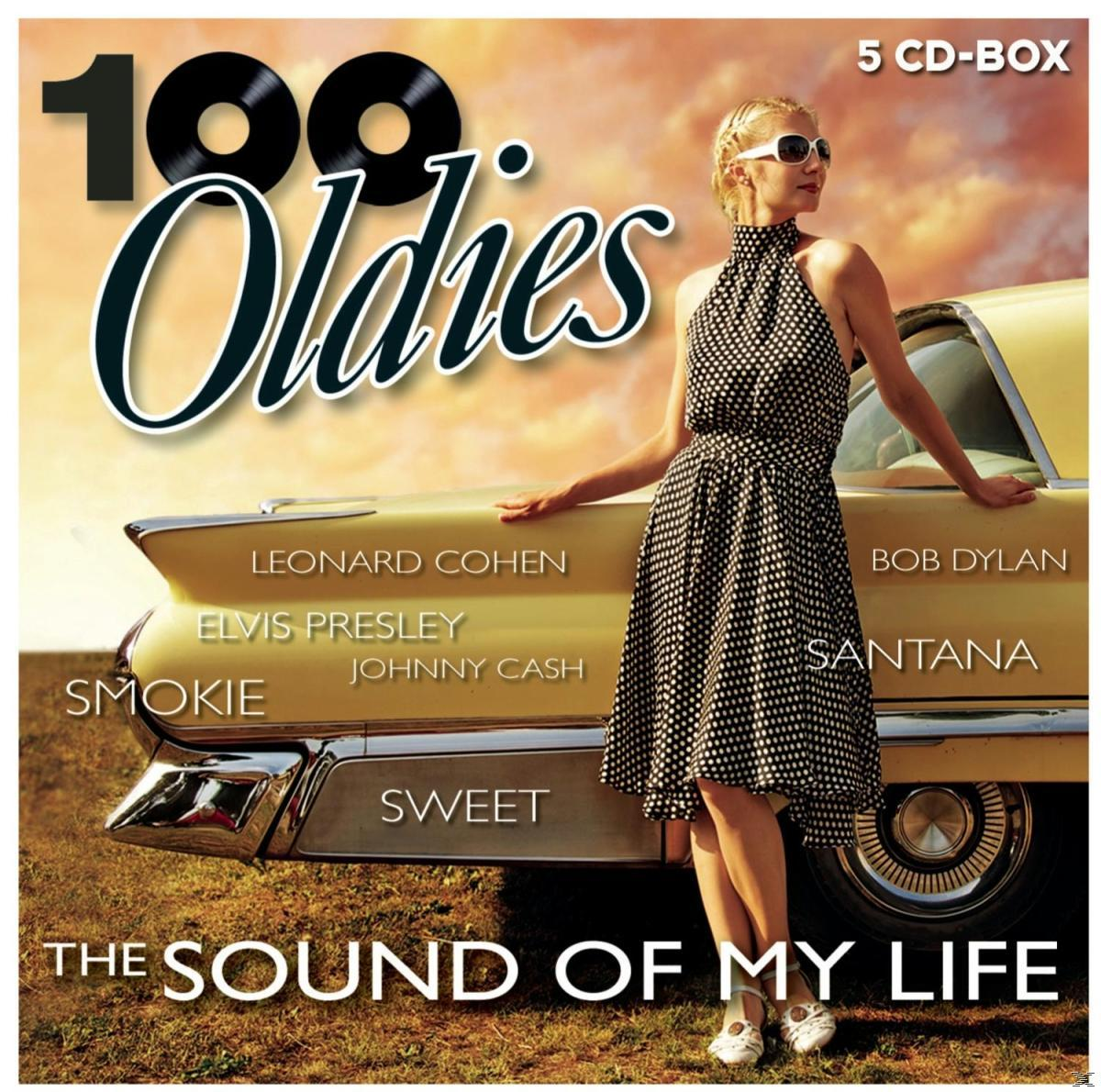 100 Oldies Albumcover: Frau mit Sonnenbrille steht an einem gelben Auto. Künstler sind auf der Seite aufgelistet.