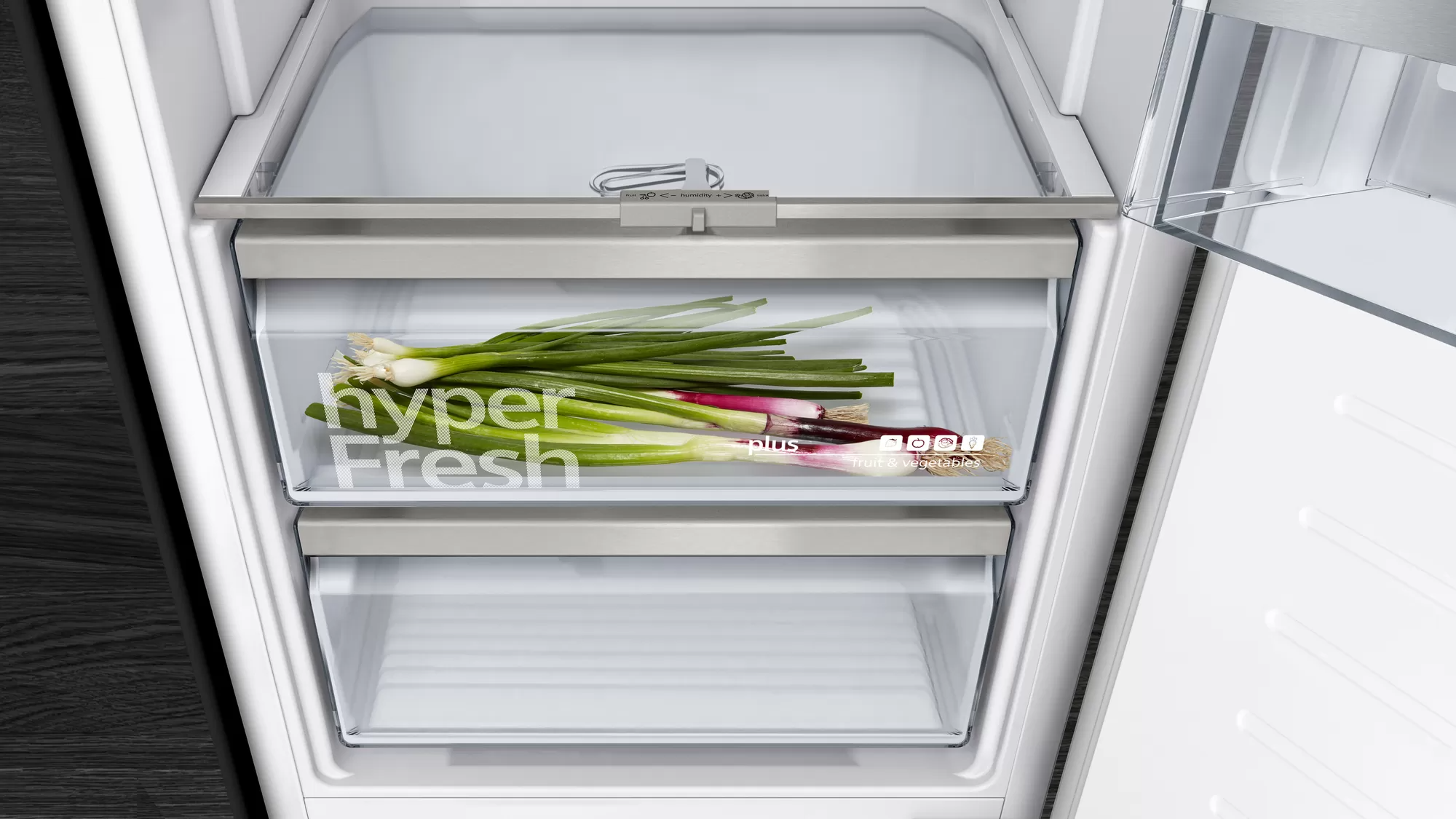 Koelkastlade met verse groene uien erin. De lade zegt 'hyper Fresh'.