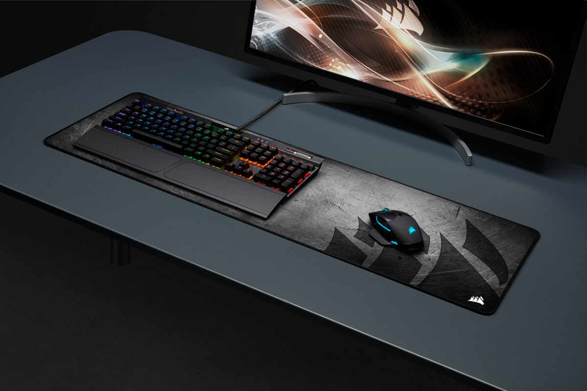 Configuration de jeu : clavier, souris et tapis de souris sur un bureau gris.