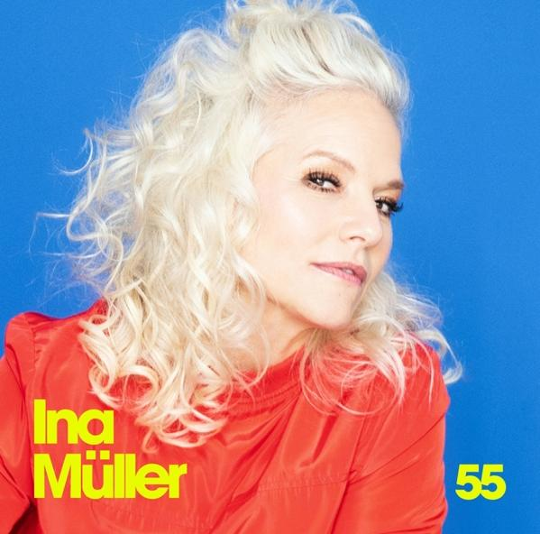 Frau mit hellem Haar und rotem Oberteil lächelt vor blauem Hintergrund, Text 'Ina Müller 55'.