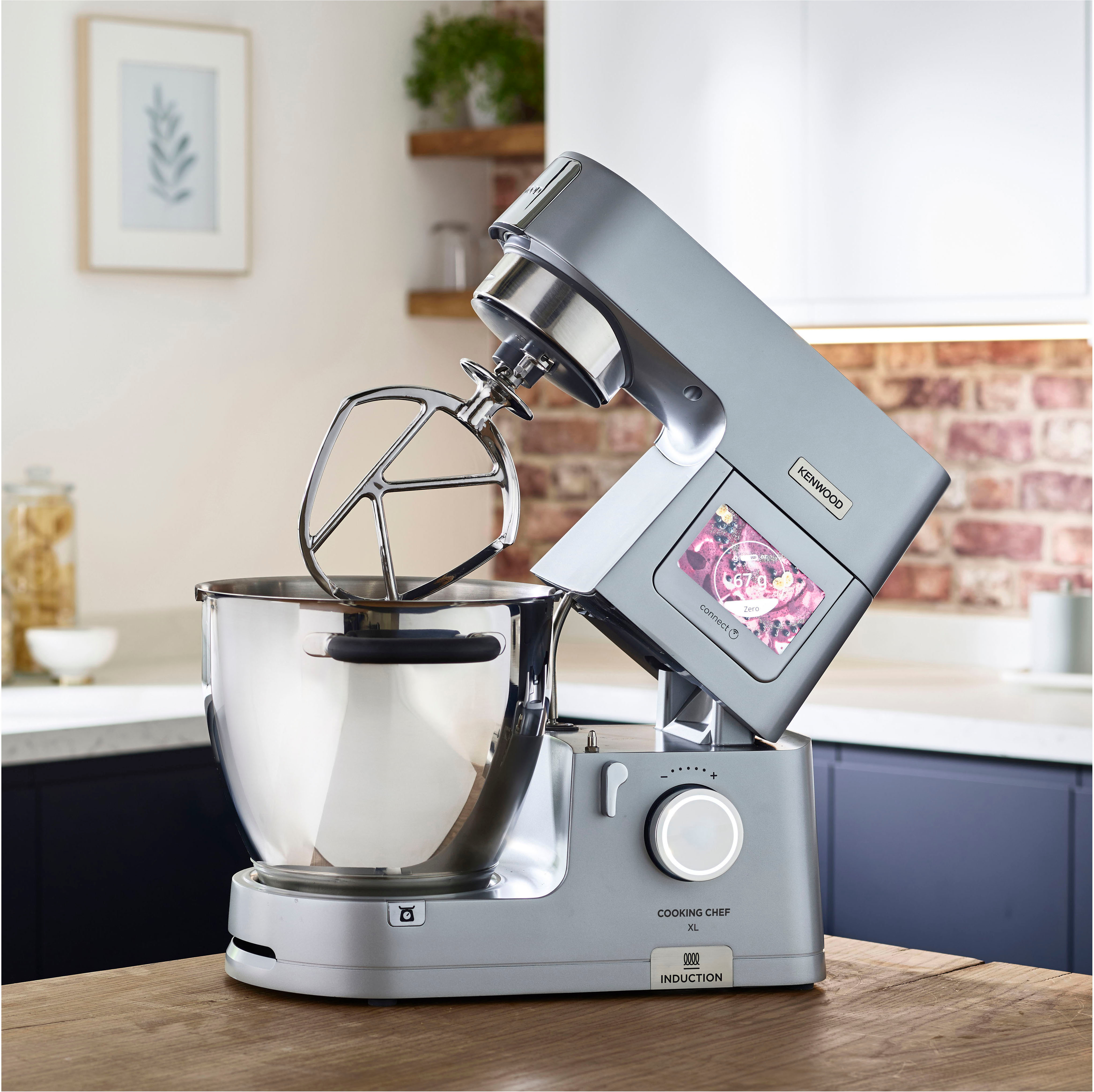 Robot da cucina Kenwood argentato con ciotola in acciaio inox su un piano di lavoro in legno.