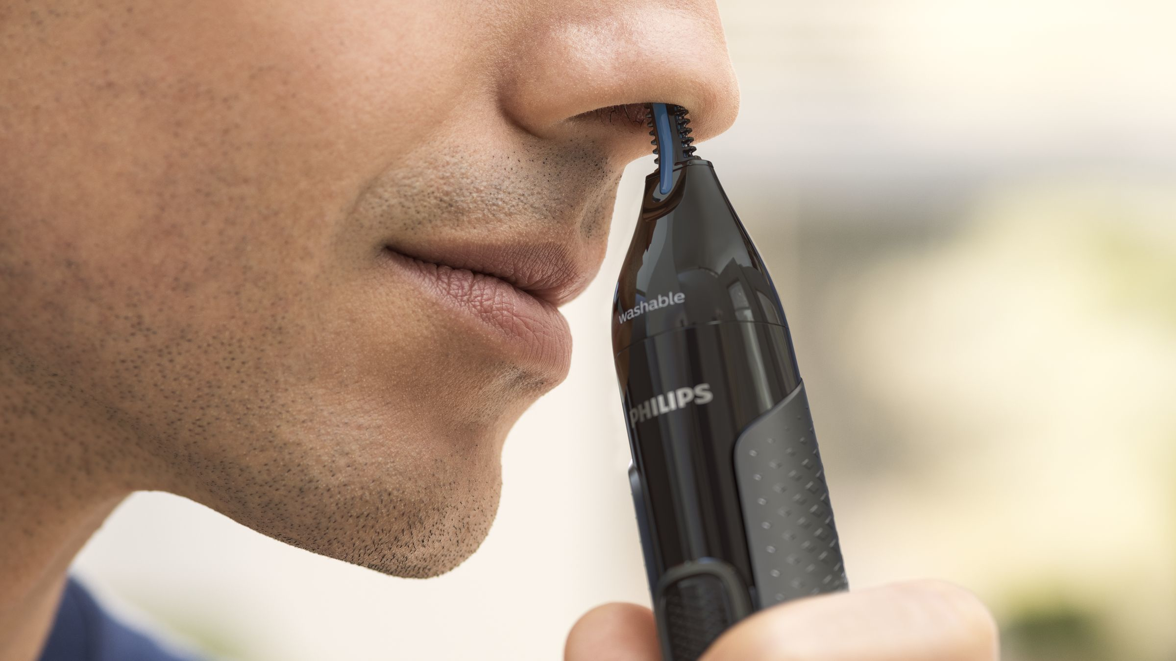 Ein Mann benutzt einen schwarzen Philips Nasenhaartrimmer.