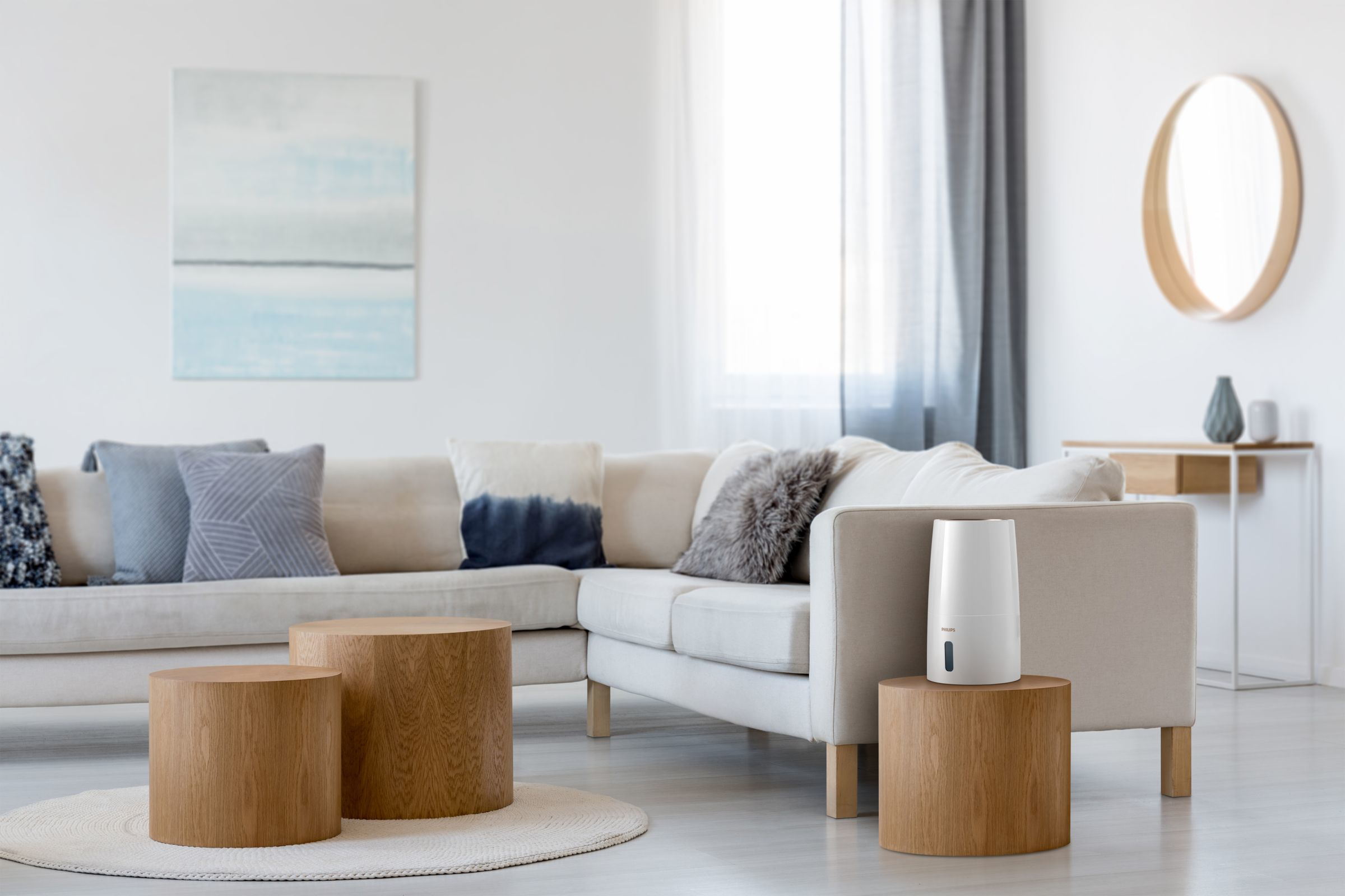 Ein Wohnzimmer mit weißem Sofa, Holztischen und einem Luftbefeuchter.