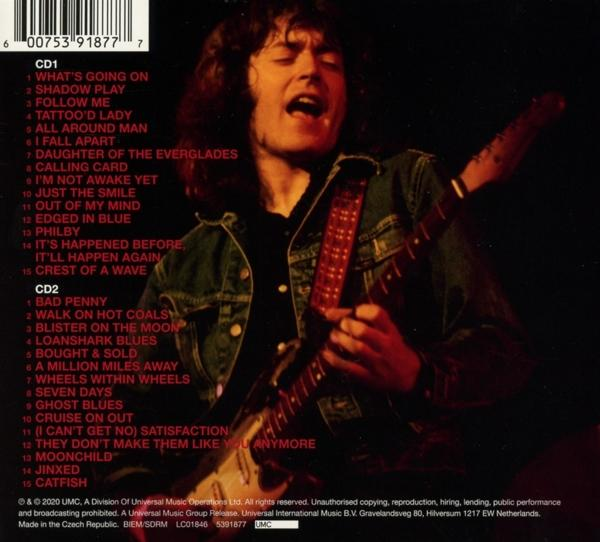 Ein Mann mit langen Haaren spielt Gitarre auf einer Bühne, Albumcover. Roter und schwarzer Text auf der Rückseite.