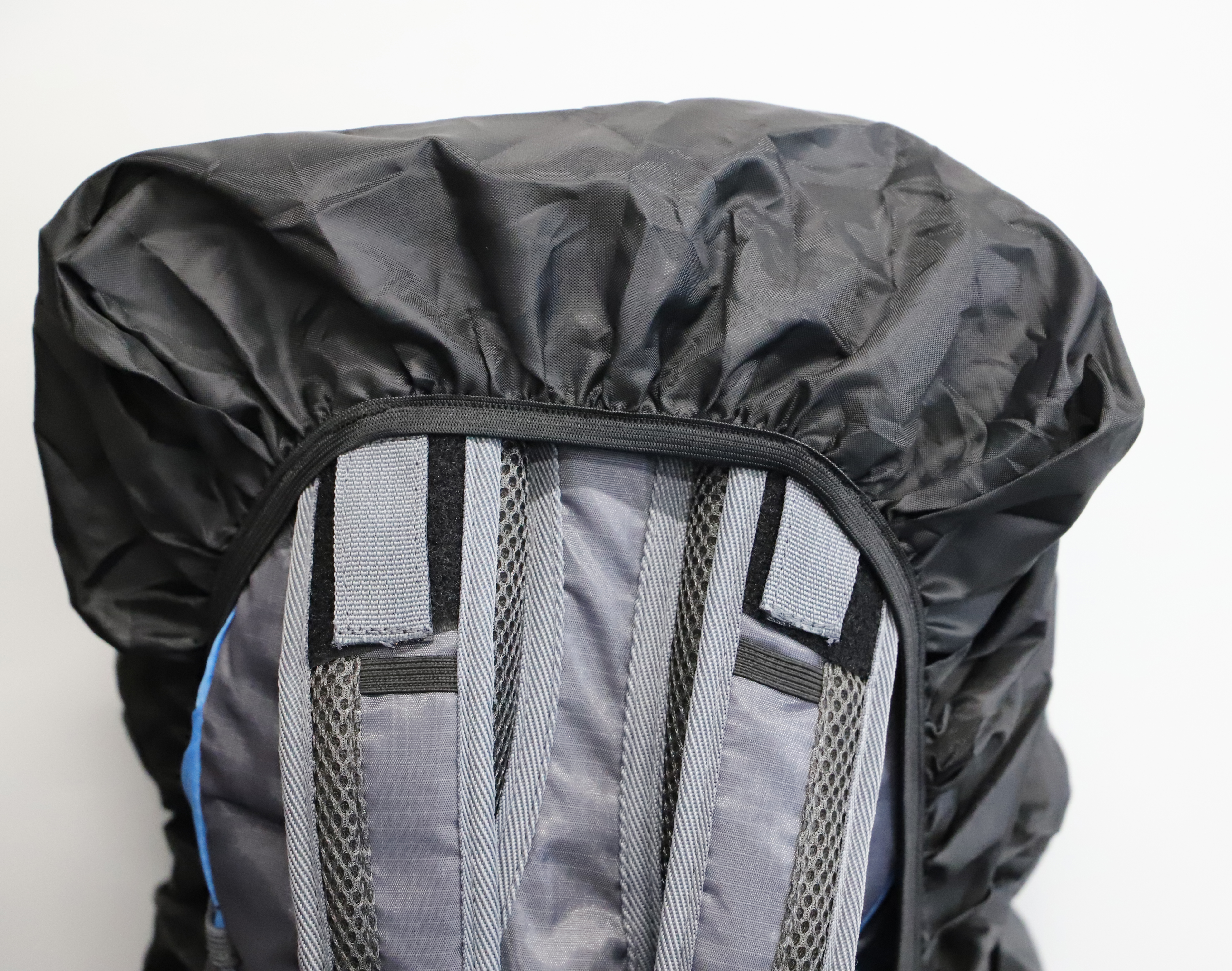 Rucksack mit schwarzem Überzug. Der Überzug hat einen Reißverschluss. Der Rucksack ist grau und blau. Weißer Hintergrund.