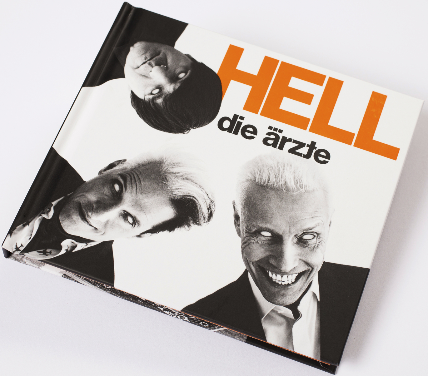 Ein Buchcover, weiß und schwarz, mit einem Foto von drei Personen und orangefarbenem Text.