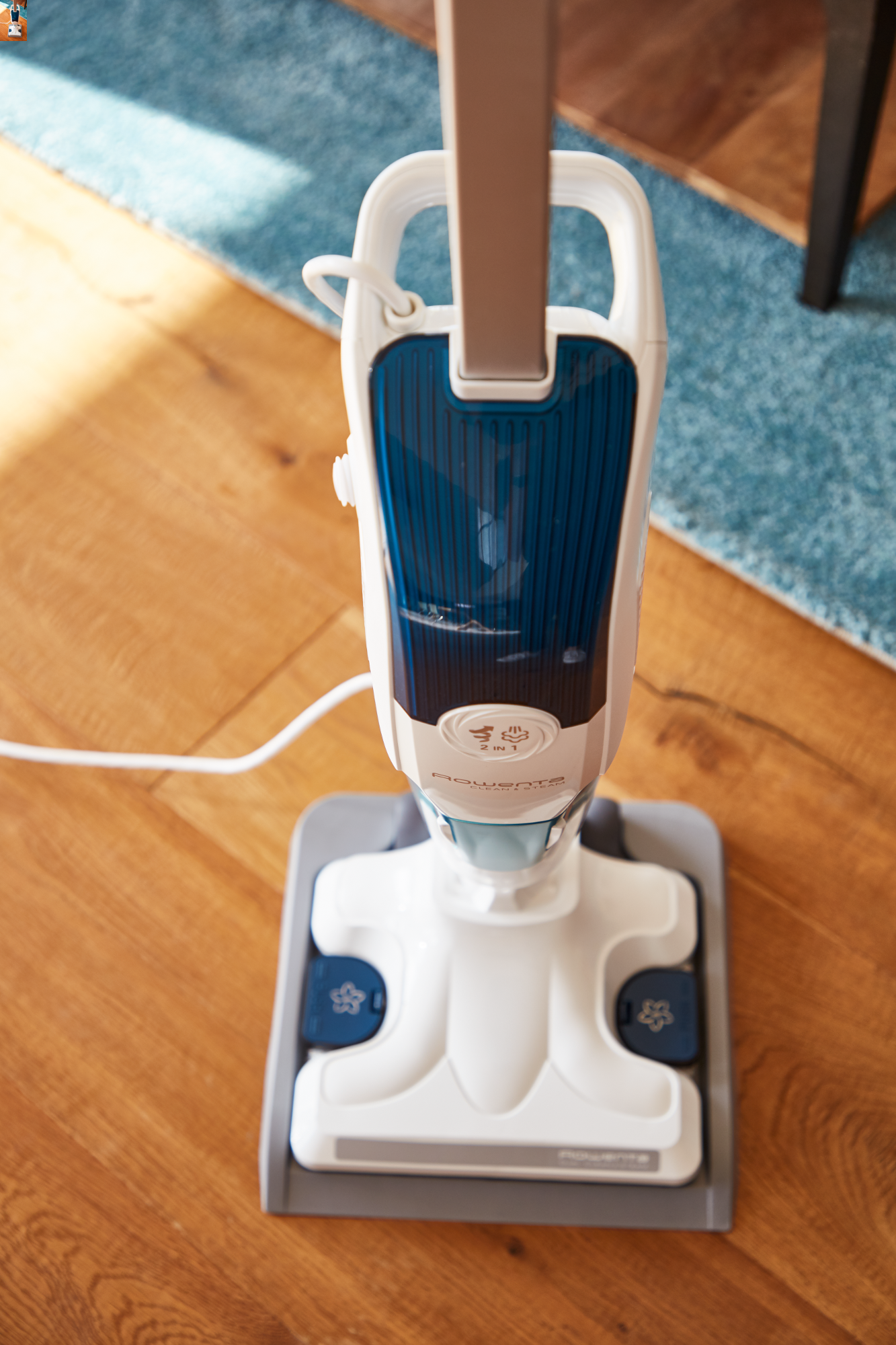 Nettoyeur vapeur vertical avec corps blanc, accents bleus et base grise.