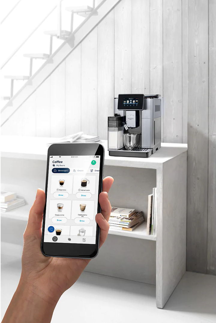 Main tenant un téléphone affiche des options de café, machine à café sur étagère.