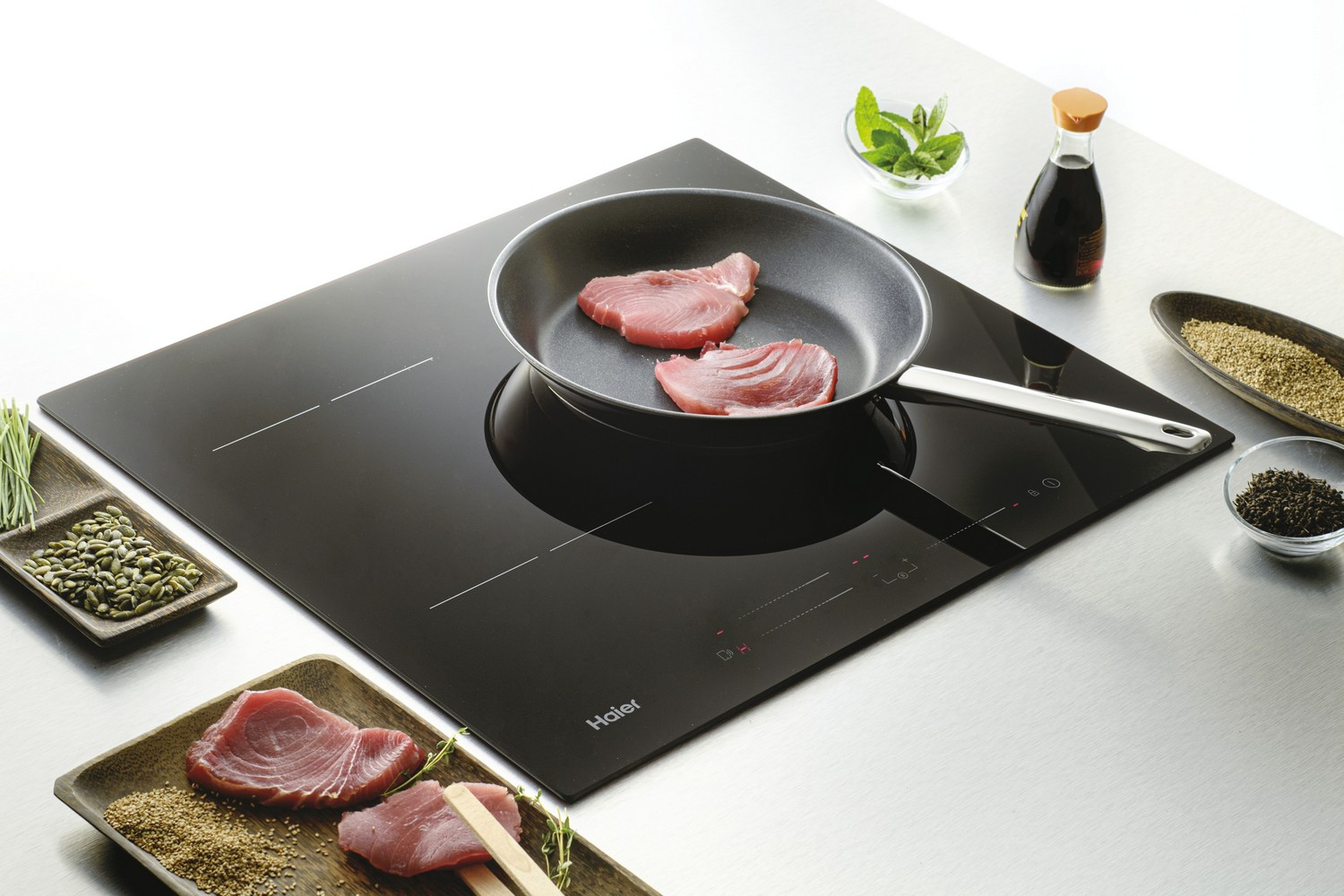 Una placa de inducción con comida e ingredientes alrededor.