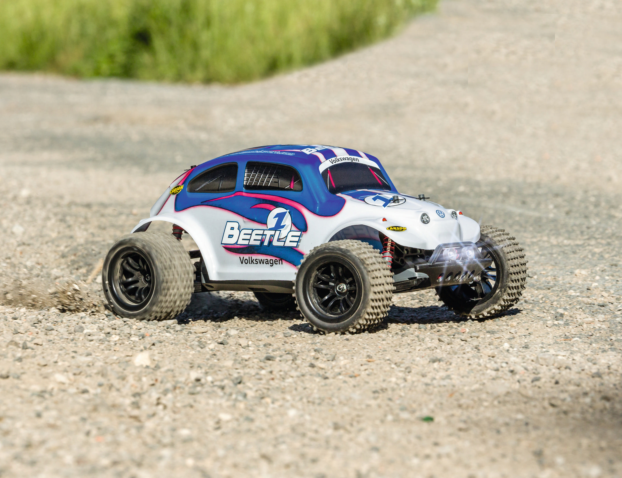 Ein ferngesteuertes Spielzeug-Volkswagen-Käfer auf einer Schotteroberfläche.