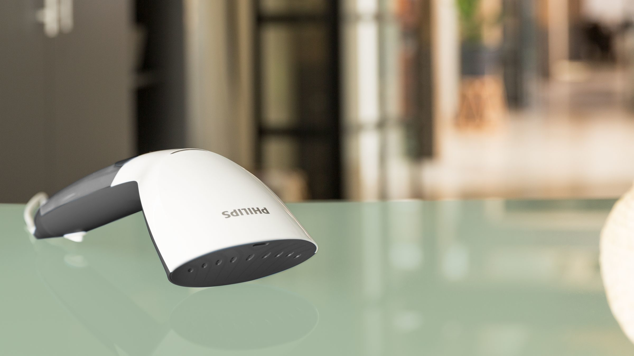 Vaporizador Philips blanco y gris sobre una superficie verde. El vaporizador está en ángulo.