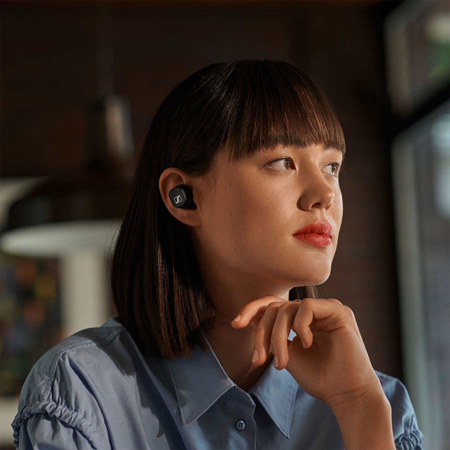 Mujer con cabello oscuro usando auriculares, mirando hacia la derecha.