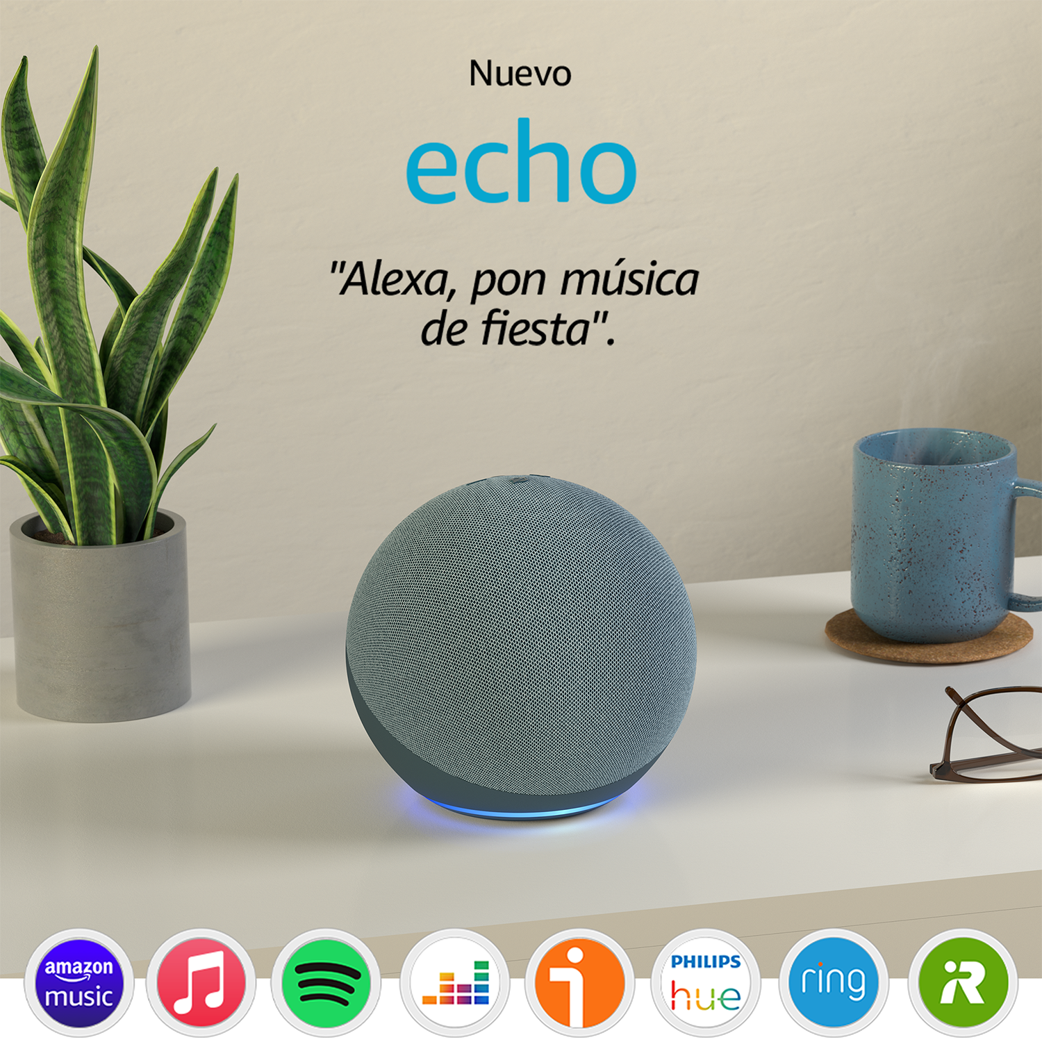 Un altavoz inteligente gris con texto en español e iconos. Una planta y una taza están en la mesa blanca.