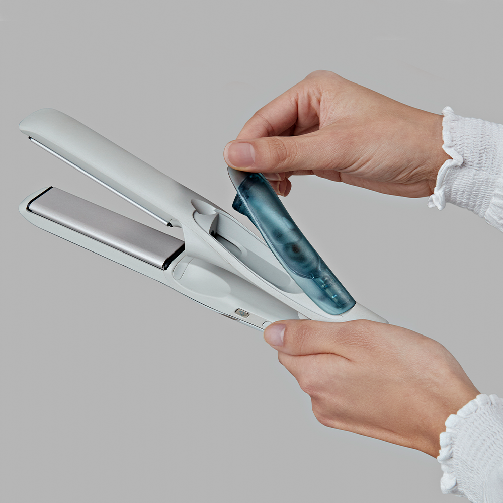 Hands holding a hair straightener and a blue water container.