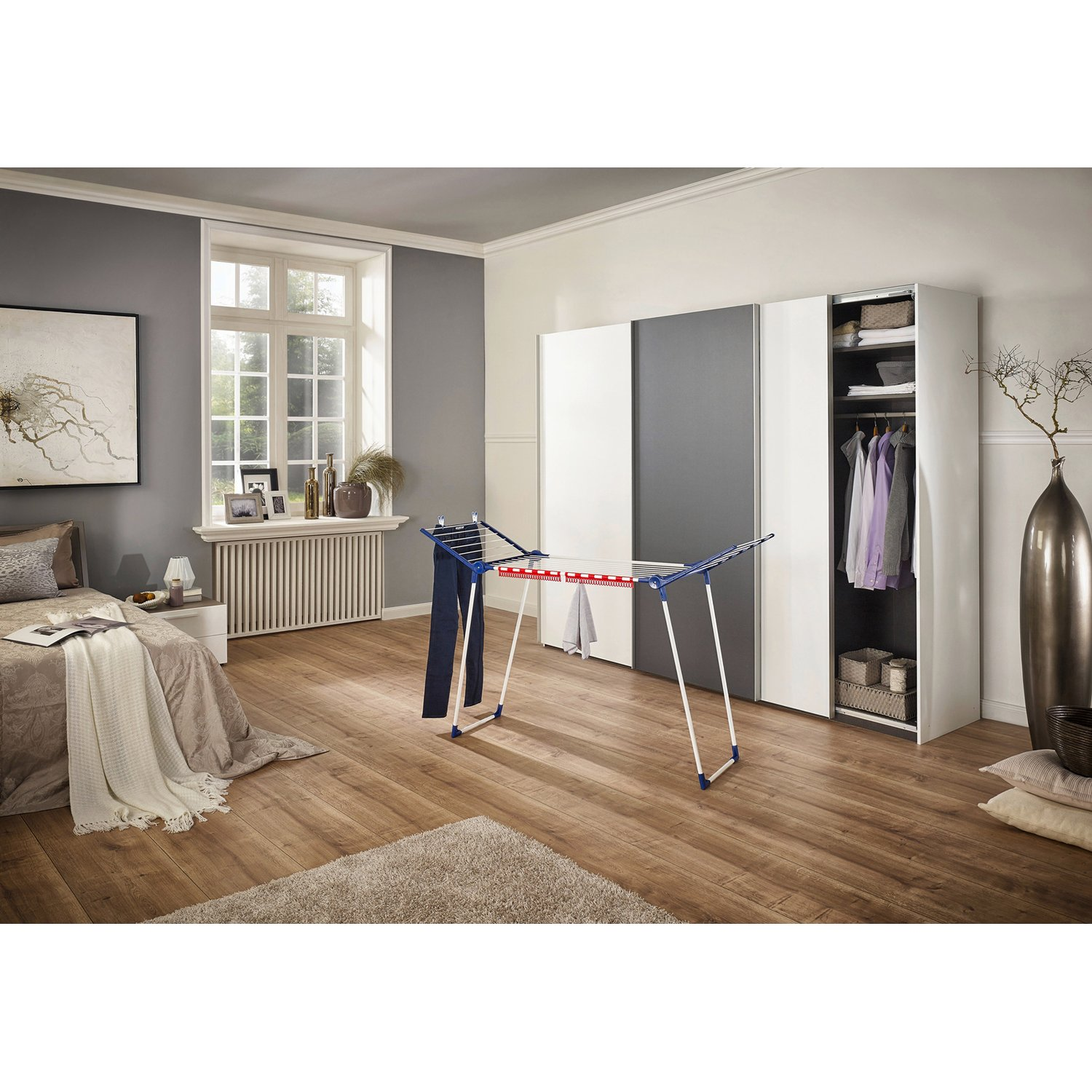 Schlafzimmer mit Wäscheständer, Bett, Fenster und Schrank.