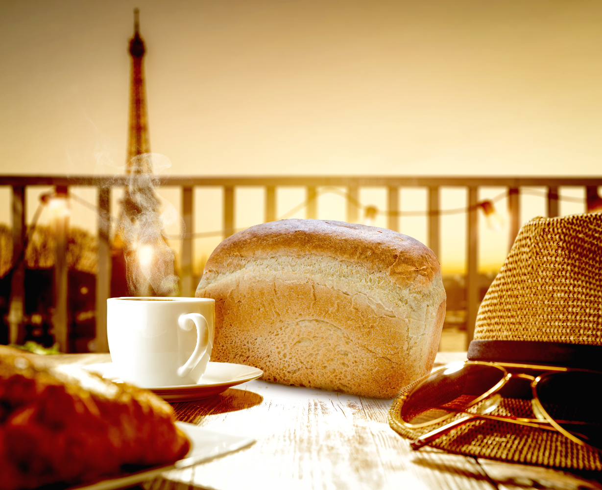 Tavolo da colazione con pane, caffè, croissant, cappello, occhiali da sole, vista Torre Eiffel.