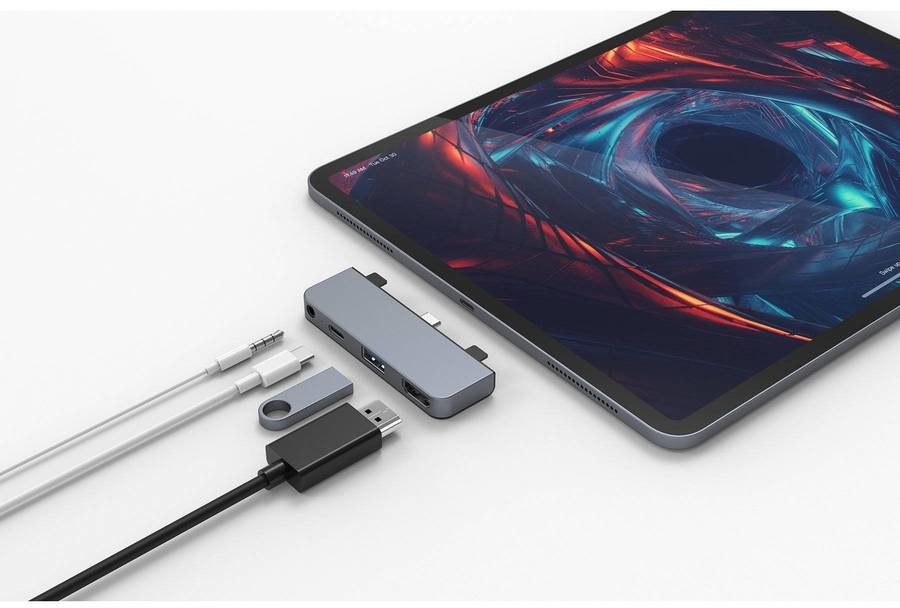 Tablet with a gray hub and connected accessories, including cables and a USB drive.