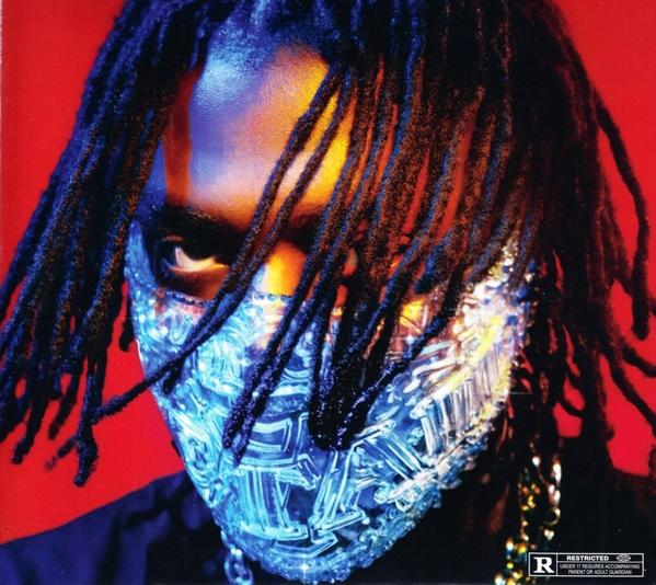A person with dreadlocks wearing a blue jeweled mask. Red background.
