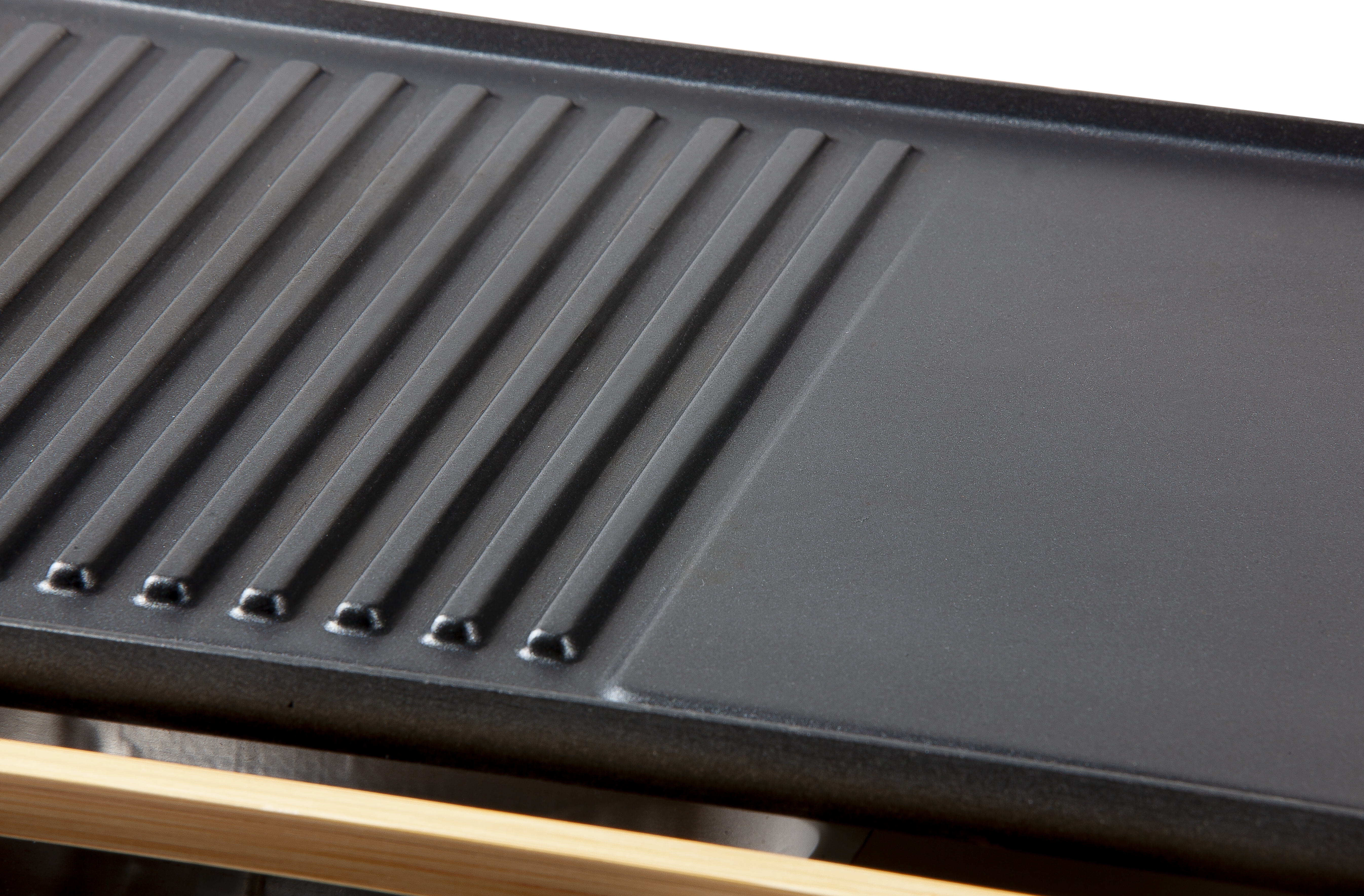Close-up of a black grill and a smooth surface. It has ridges on one side and a bamboo handle.