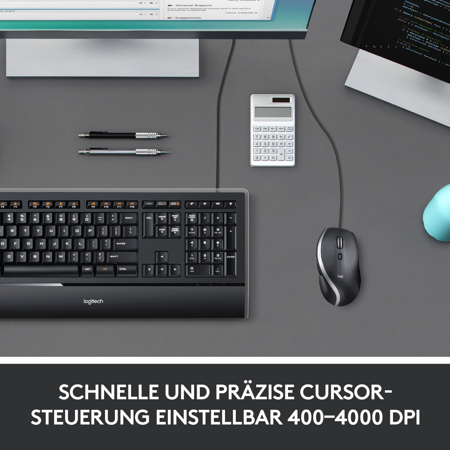 Schwarze Tastatur und Maus auf grauer Oberfläche. Ein Taschenrechner und Stifte sind sichtbar. Monitor im Hintergrund.